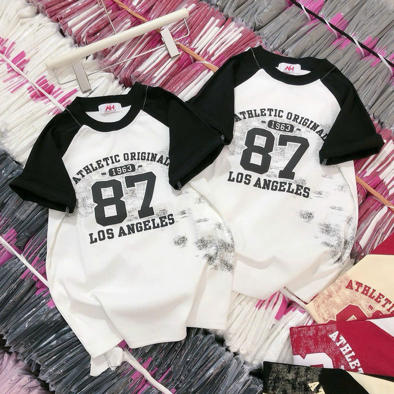 Phối màu trắng–đen kiểu raglan với hoạ tiết chữ/số in mặt trước