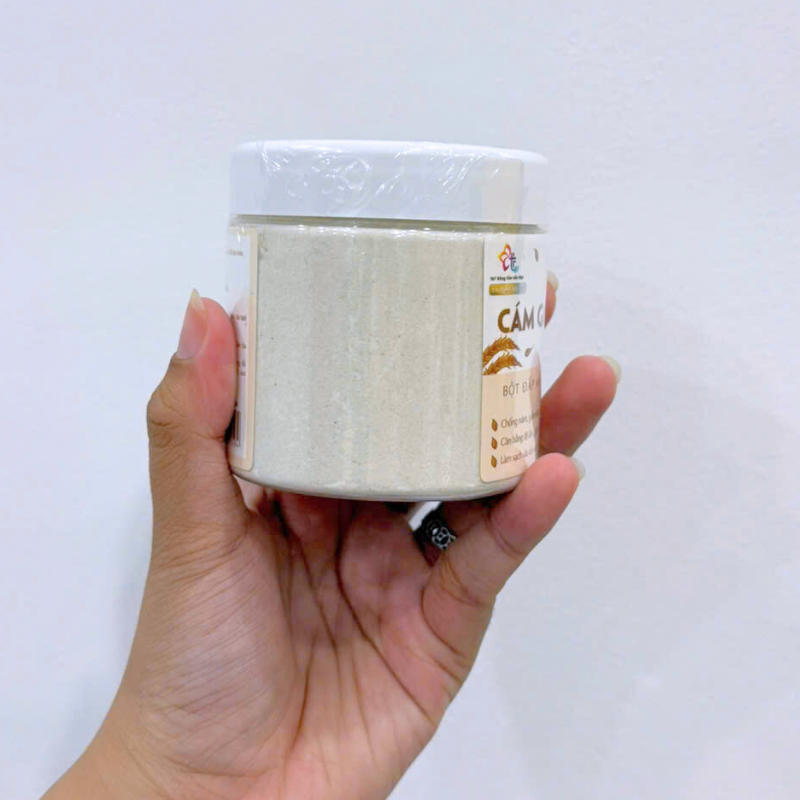 Bột đắp mặt cám gạo trong hũ nắp trắng, thân nhựa nhìn rõ lượng bột bên trong.