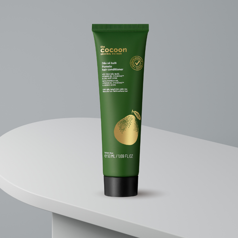 Mặt trước tuýp xanh có chữ “Pomelo hair conditioner” và hình bưởi màu vàng.