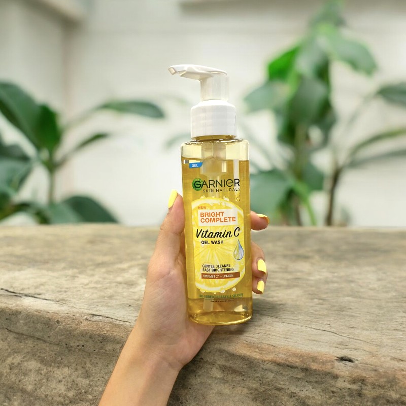 Chai gel thon gọn cầm một tay, nổi bật trước nền cây xanh