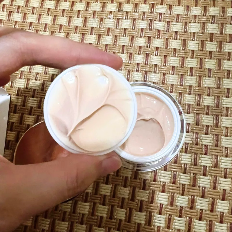 Hũ kem mở nắp với chất kem màu hồng be, bề mặt mịn mềm