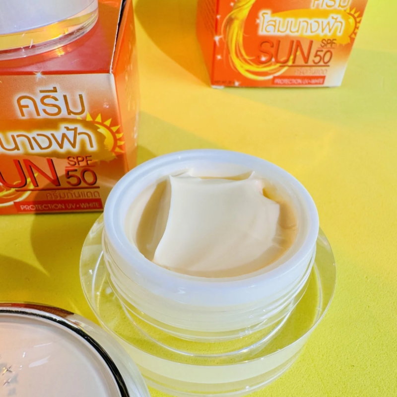 Hũ kem mở nắp trên nền vàng, phía sau là hộp cam SUN SPF 50