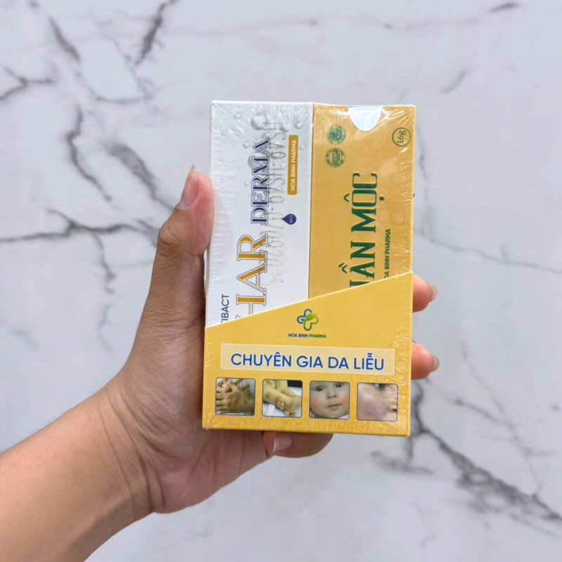 Hai hộp tông vàng trắng được cầm gọn trong một bàn tay