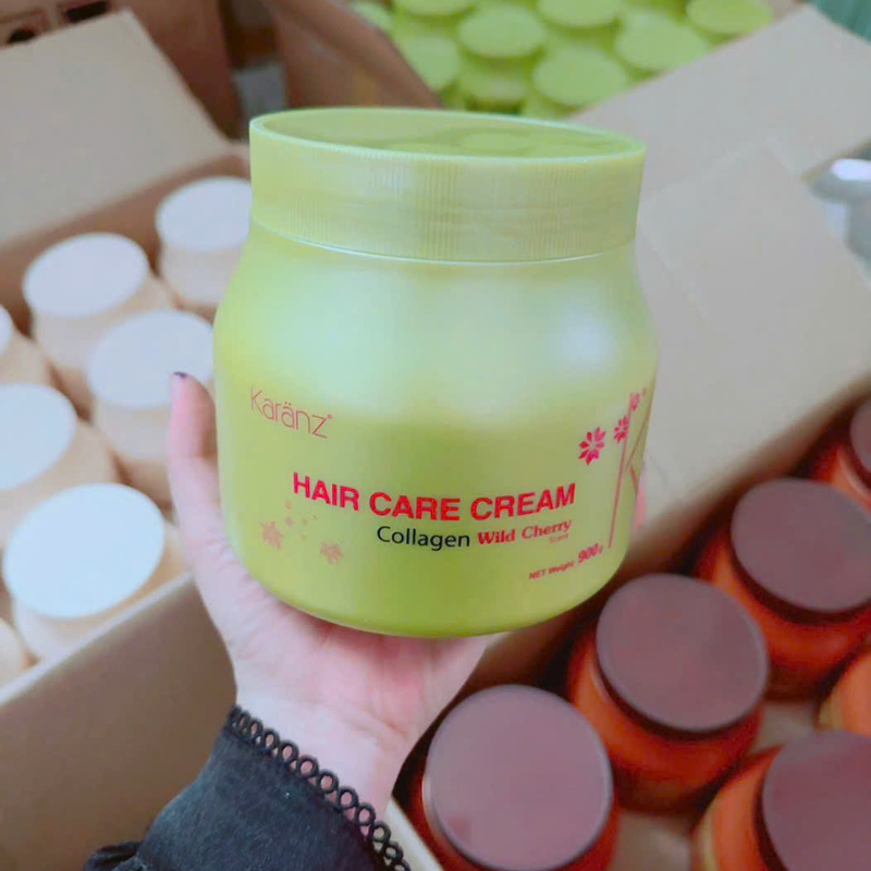 Một tay cầm hũ kem giữa nhiều hộp và nắp sản phẩm xung quanh