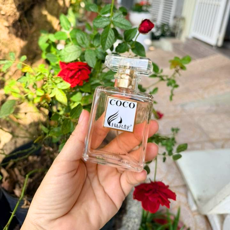 Nước hoa Charme Coco được cầm trên tay trước bụi hồng đỏ ngoài sân