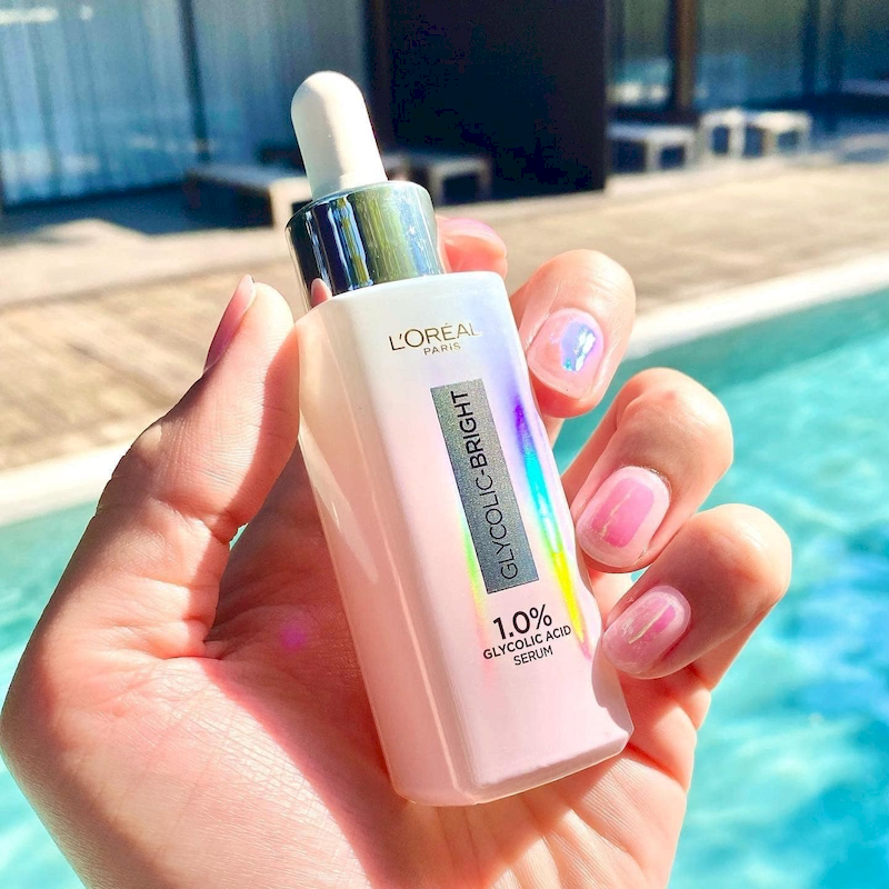 Serum loreal hồng cầm trên tay dưới nắng, thân chai phản quang màu hồng