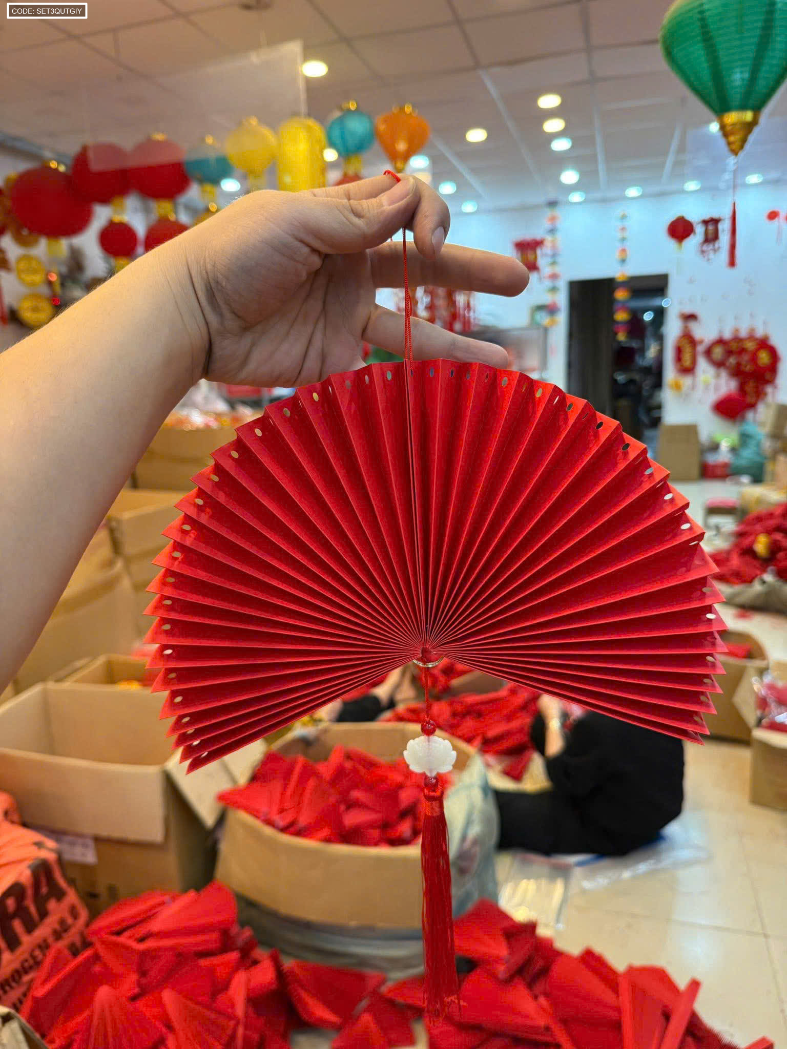 Cận cảnh quạt giấy đỏ có dây treo và tua rua