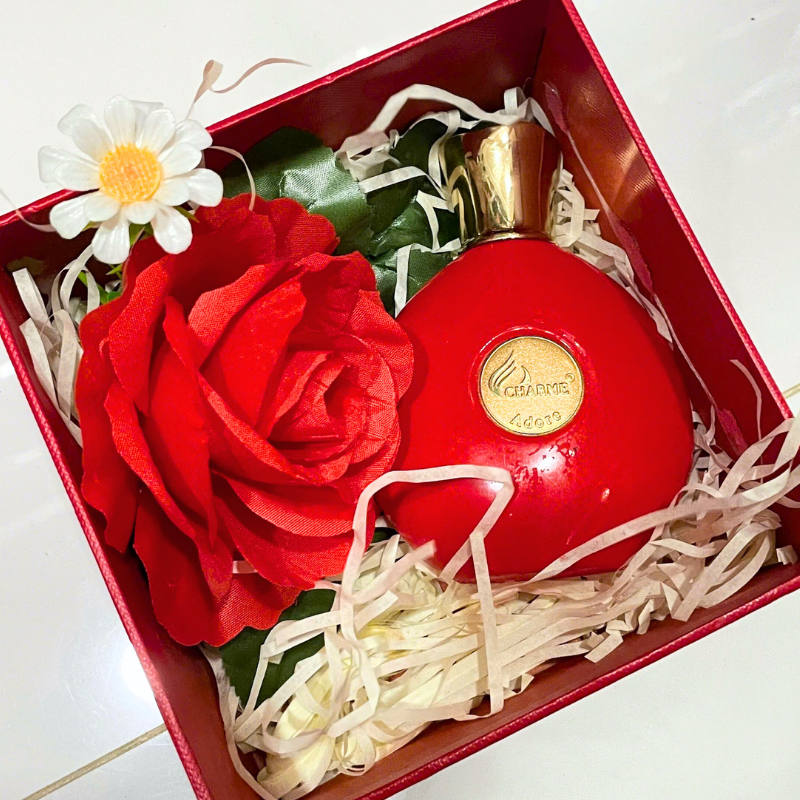Bố cục set quà gồm chai nước hoa, hoa trang trí và giấy rơm lót hộp.