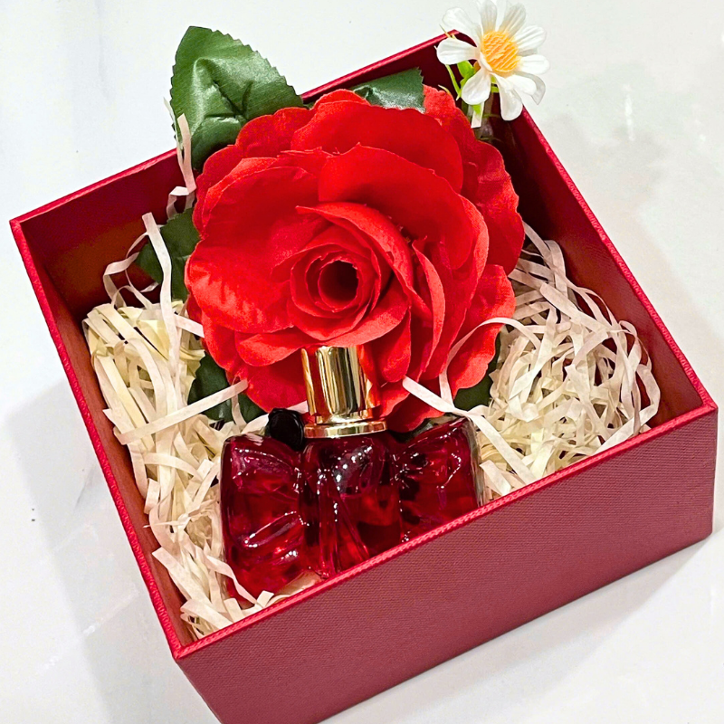 Bố cục set quà với hộp đỏ, hoa trang trí và chai nước hoa bên trong
