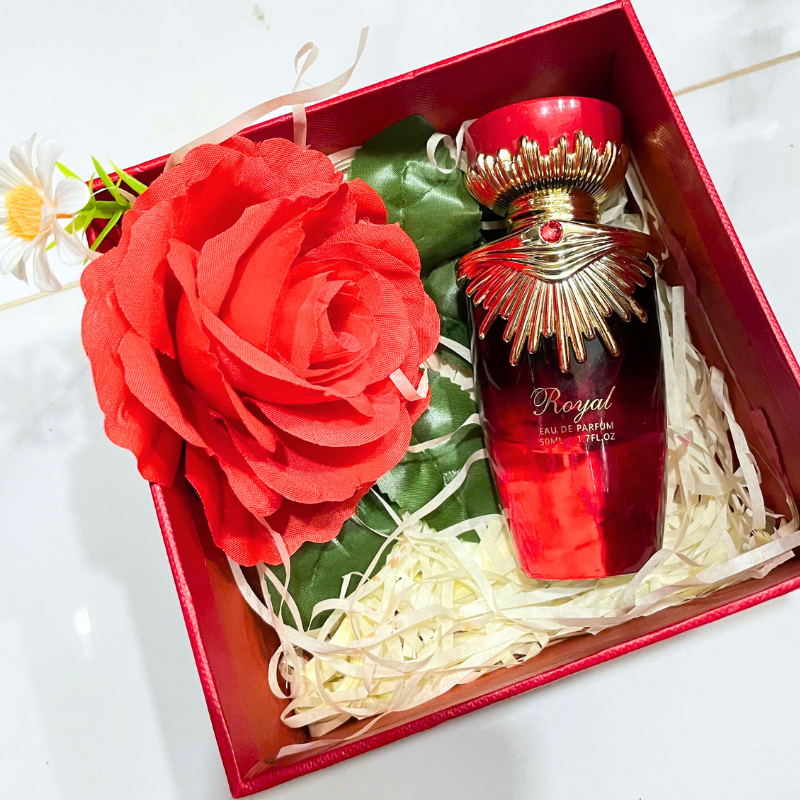 Set quà gồm chai nước hoa, hoa trang trí và giấy rơm trong hộp đỏ.