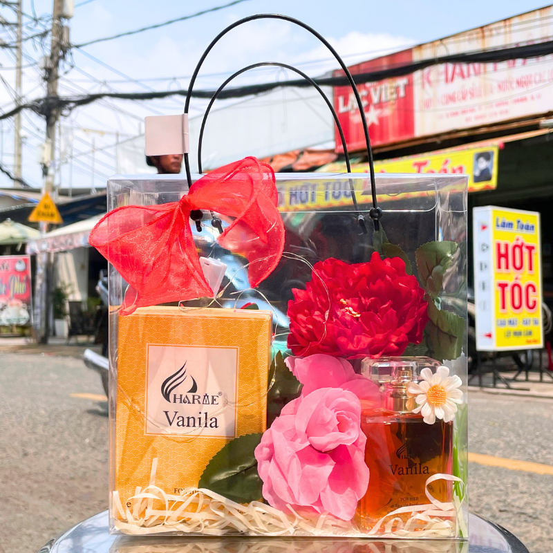 Toàn cảnh set quà với chai nước hoa, hộp, hoa trang trí và nơ đỏ