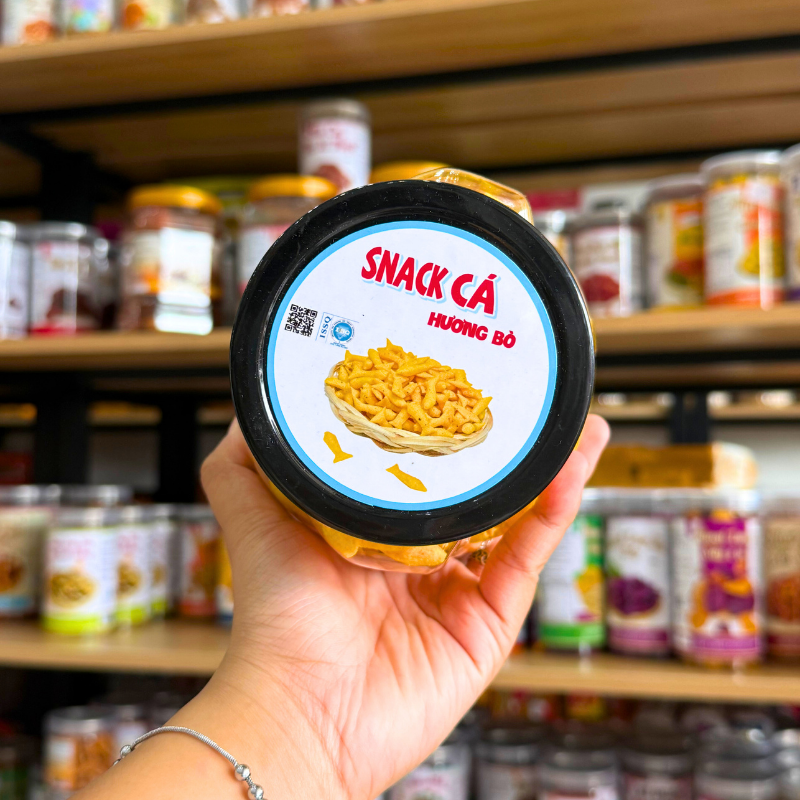 Nhãn nắp hộp thể hiện tên snack cá hương bò