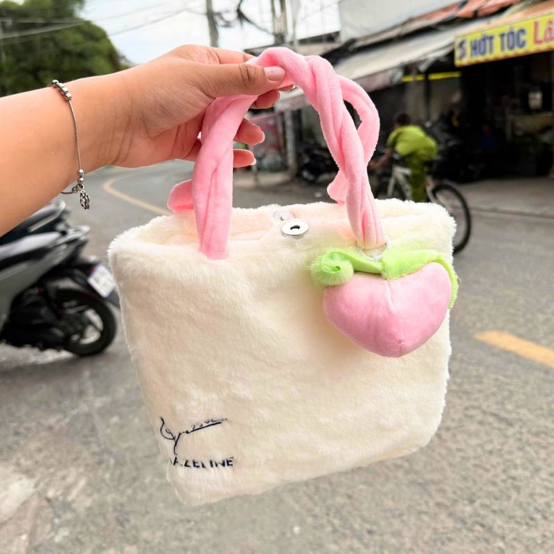 Mặt trước túi lông trắng với quai hồng bện và charm trái tim