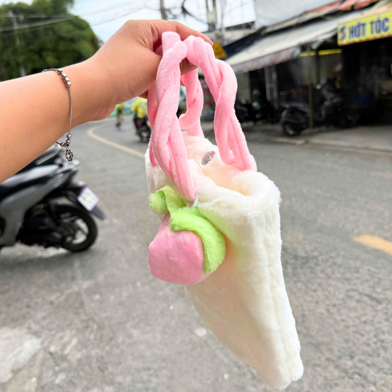 Góc nhìn hông túi, thấy rõ chi tiết charm và phần miệng túi có nút bấm